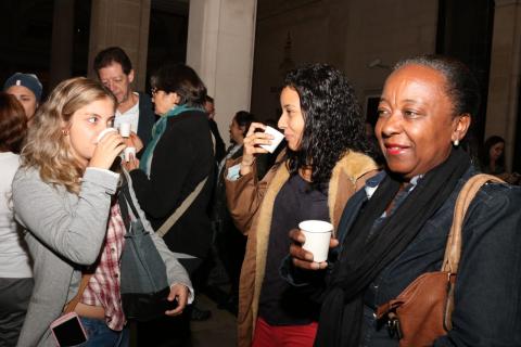 Público toma café no evento. Em primeiro plano, três mulheres bebem café em copinhos. #Pracegover