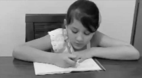 Menina escreve em caderno. #Paratodosverem