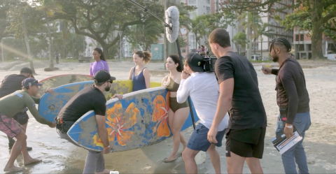 pessoas seguram prancha durante filmagem #paratodosverem