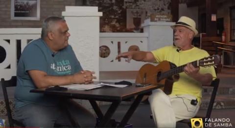 dois homens conversam em mesa durante vídeo #paratodosverem