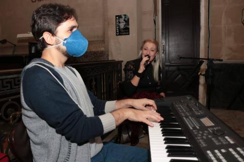 músico toca ao piano acompanhado p or cantora. #paratodosverem