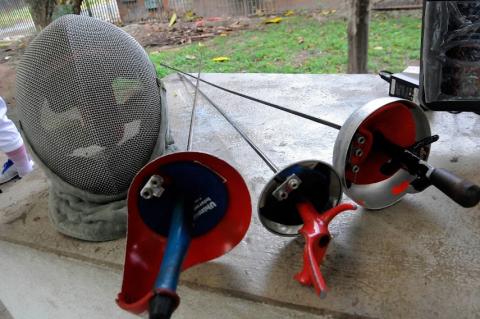 Máscara e espadas, equipamentos usados na esgrima. #paratodosverem