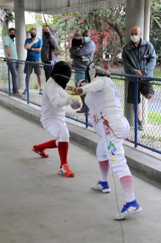 Pessoas observam duas pessoas jogando esgrima. #paratodosverem