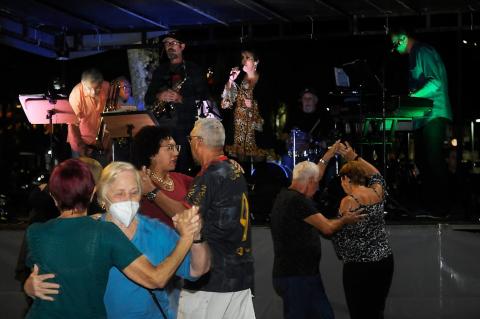 pessoas dançando e banda tocando ao fundo #paratodosverem