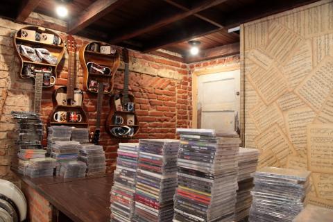 loja com CDS sobre mesas e violões na parede. #paratodosverem