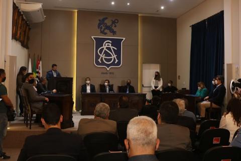 Novo presidente da ACS Jovem discursa em púlpito observado por autoridades no entorno. #pracegover
