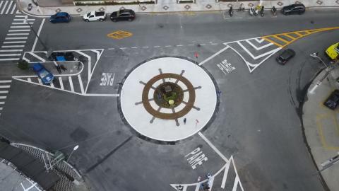 Vista aérea da praça, que tem desenho de um timão no piso, e das vias da rotatória com a sinalização de solo. 