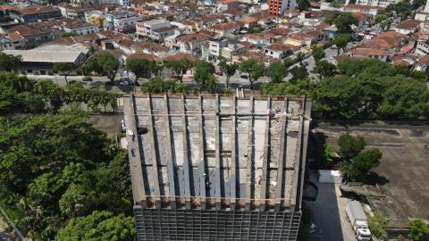 Vista aérea da cobertura do teatro, com vegetação à esquerda e edificações ao fundo. #Paratodosverem