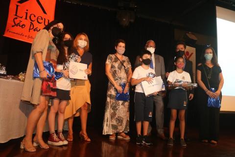 Alunos recebem premiação no palco #paratodosverem