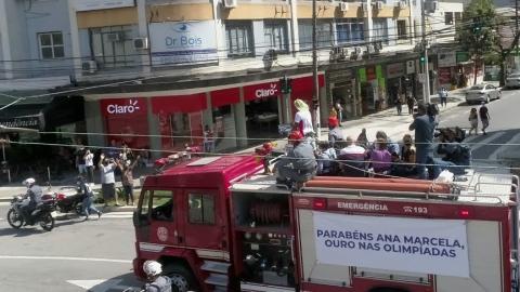 Atleta no alto do carro do Bombeiros é reverenciada por munícipes na Praça da Independência. #pracegover