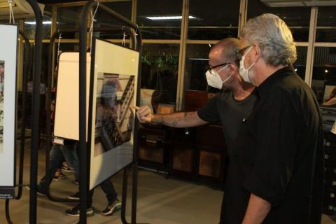 Dois homens olham foto na exposição  #paratodosverem