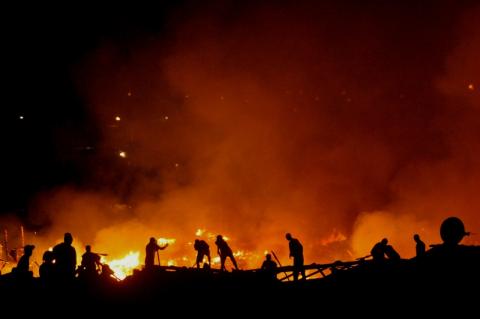 Pessoas atuam próximo a chamas de incêndio. #pracegover