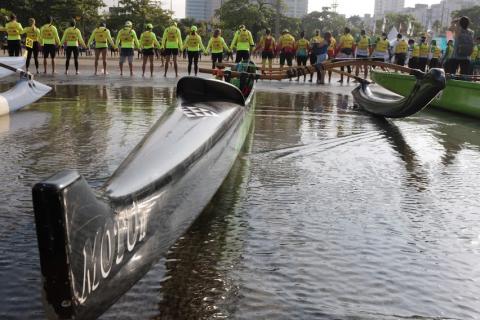canoa havaiana na água om remadores de mãos dadas atrás #paratodosverem