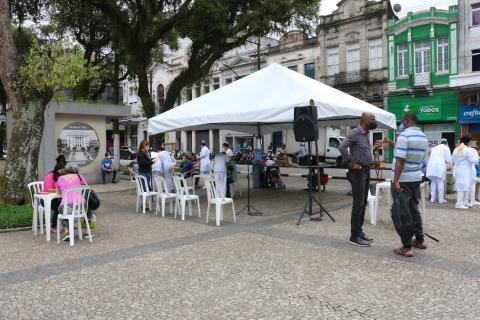 Tenda armada na praça com pessoas atendendo #paratodosverem