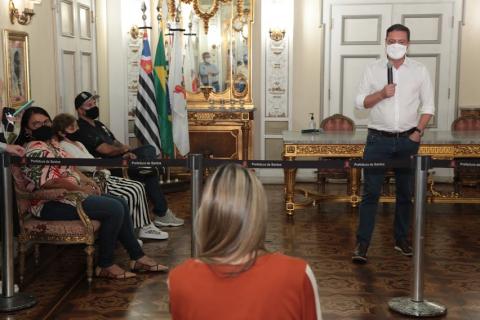 apresentação do projeto no Paço Municipal, com o prefeito em pé falando a algumas pessoas sentadas. #paratodosverem