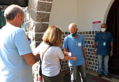 homem usa termômetro para medir temperatura de visitantes na entrada do parque. #paratodosverem