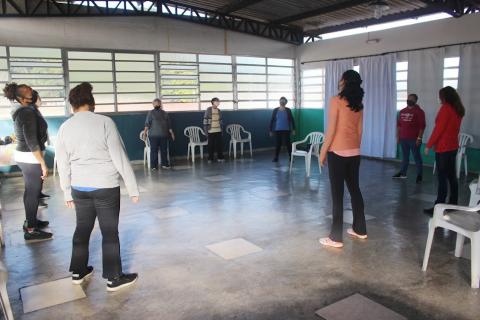 pessoas estão em pé num salão fazendo movimentos circulares com a cabeça. #paratodosverem