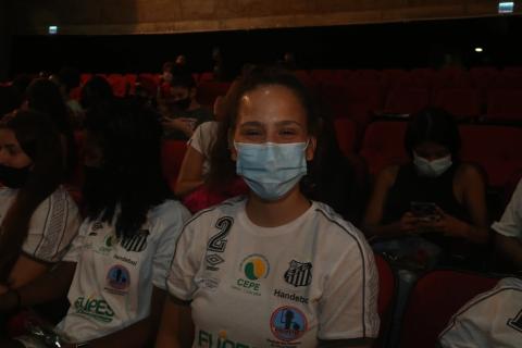 A atleta Ana Beatriz olha para a foto. Ela usa máscara. #paratodosverem
