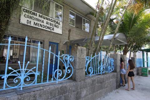 a fachada da escola com placa na frente onde se lê creche municipal candinha ribeiro de mendonça. #paratodosverem