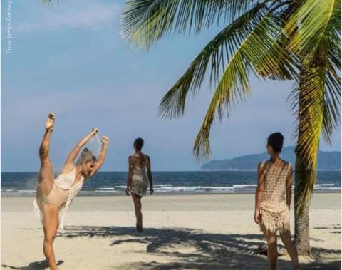 Mulher dançam ballet na areia da praia com mar ao fundo #paratodosverem