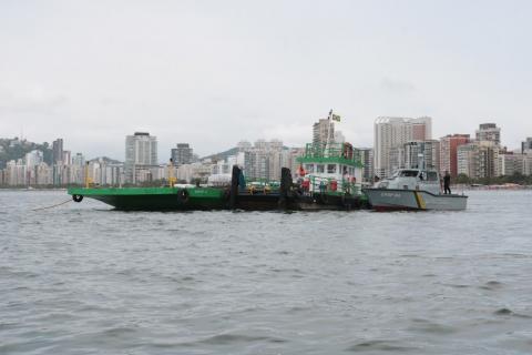 Balsa no mar e prédios da orla ao fundo. #paratodosverem