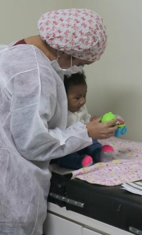 mulher segura e mostra brinquedo para bebê. #paratodosverem