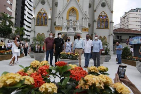 autoridades posam para foto na frente da igreja. Em primeiro plano está uma floreira. #paratodosverem