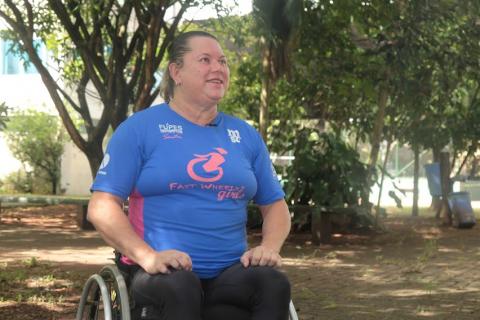 Beth sorri sentada na cadeira de rodas. #paratodosverem