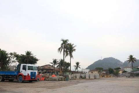 terreno vazio com caminhão na lateral e construções ao fundo. #paratodosverem