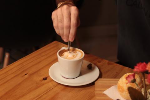 Mão mexendo numa xicara de café #paratodosverem