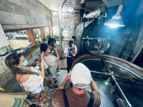 Pessoas tiram foto de mulher fazendo café #paratodosverem