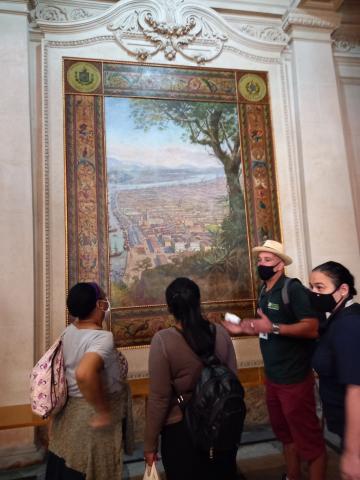 Visitantes observam pintura no Museu do Café. #pracegover