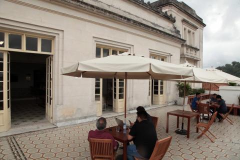 área externa da cafeteria, com os ombrelones abertos e pessoas sentadas. #paratodosverem