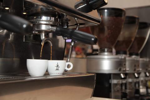 café saindo de dois bicos de máquina e enchendo duas xícaras. #paratodosverem