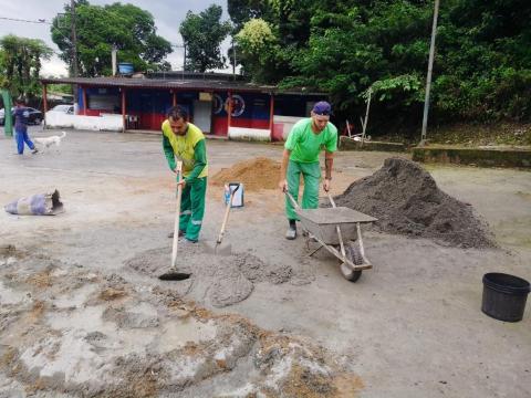 homens uniformizados preparam massa para fazer calçada. #paratodosverem