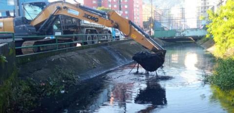 braço mecânico de caminhão estã removendo lama de canal. #paratodosverem