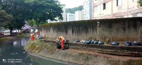homens trabalhando em talude de canal. Há sacos embalados na margem. #paratodosverem