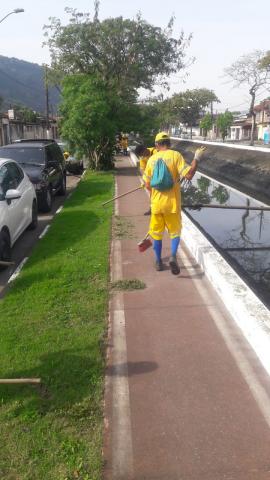 Dois profissionais fazendo serviço em jardim ao lado de ciclovia #paratodosverem