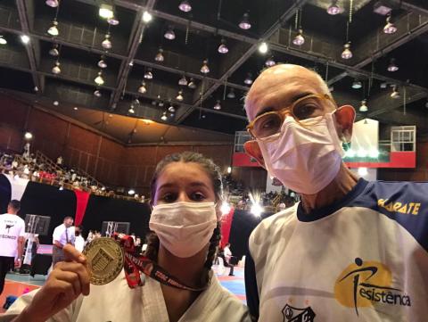 Giovana exibe medalha de ouro ao lado do treinador. #pratodosverem