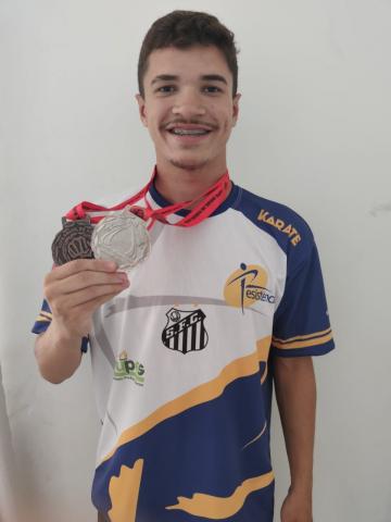 Kaique Mortari Duarte posa para foto segurando a medalha na mão direita