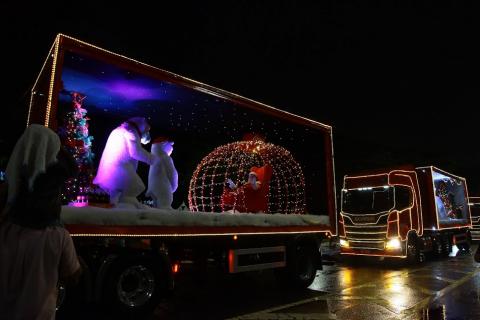 Caminhões decorados com motivos natalinos percorrem rua. #paratodosverem