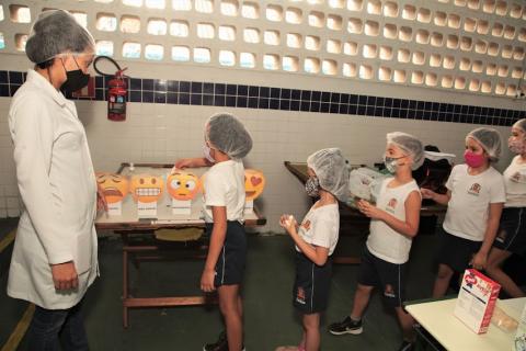 crianças fazem fila para escolher emoji onde indicam a 'avaliação' do cardápio. #paratodosverem