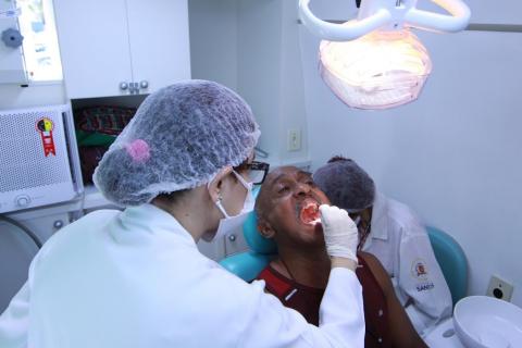 dentista examina boca de homem no consultório #paratodosverem