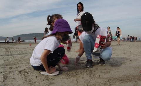 crianças recolhendo lixo na areia #paratodosverem