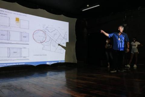 Apresentação de projeto em telão. Homem está apontando para a tela onde consta o desenho de um projeto. #paratodosverem