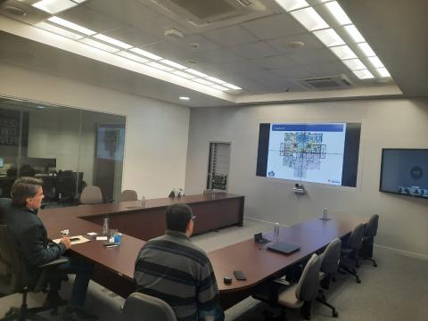 Duas pessoas olham para o monitor, onde aparece imagens dos representantes de Recife. #paratodosverem