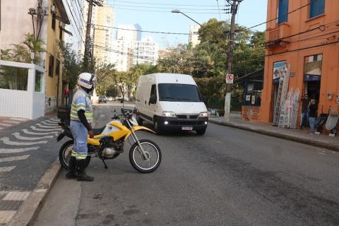 Agente da CET com a moto estacionada fiscaliza via. #paratodosverem