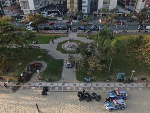 Foto aérea de praça na orla da praia, cercada por jardim e com viaturas da guarda municipal. #paratodosverem