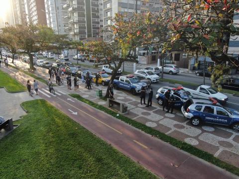 Em primeiro plano ciclovia e ao lado agentes e guarda e viaturas. #paratodosverem