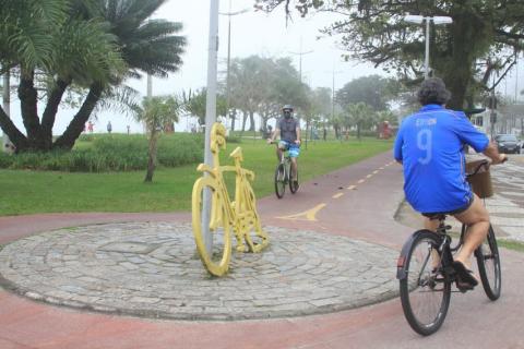 Ciclista passa em rotatória da ciclovia que tem monumento de uma bicicleta. #paratodosverem